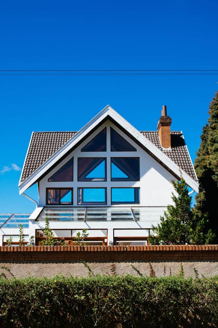 gallery-5 A modern A-frame house with large windows against a clear blue sky, showcasing contemporary architecture.
