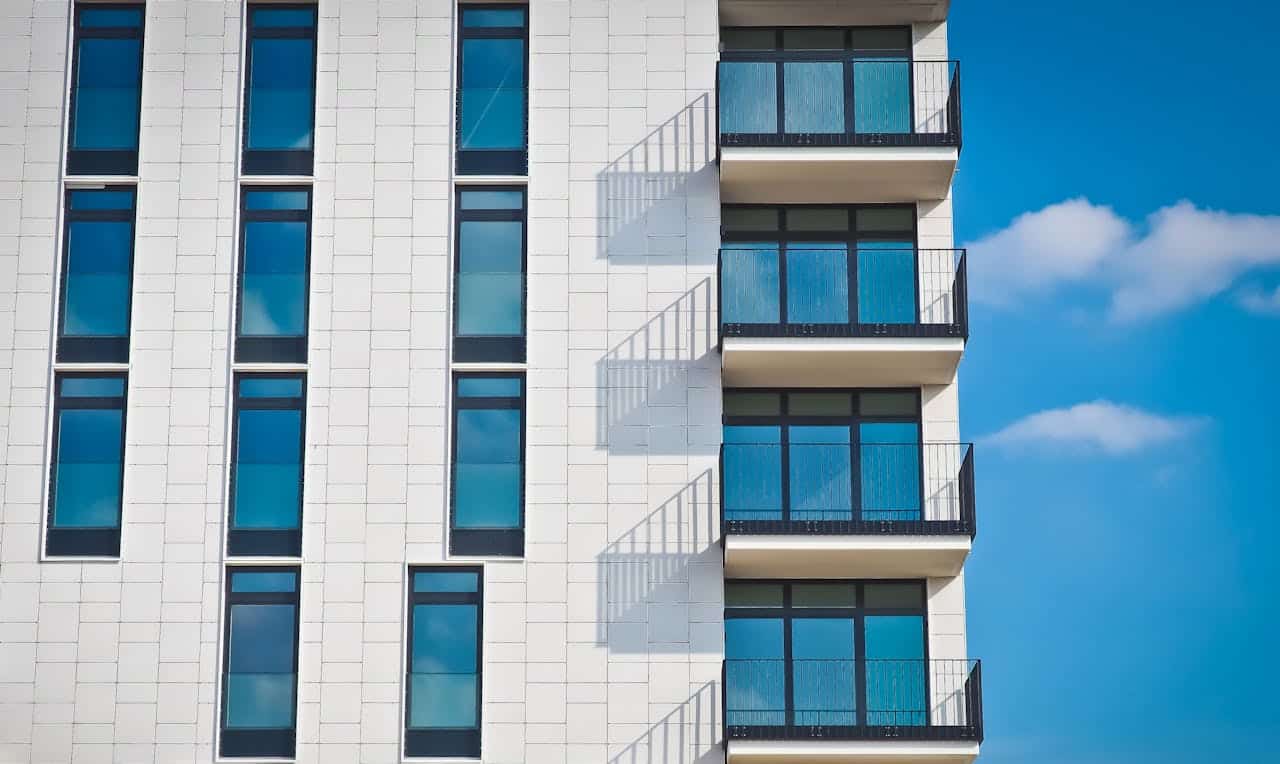 why-choose-us Contemporary urban apartment building with framed glass windows against clear blue sky.